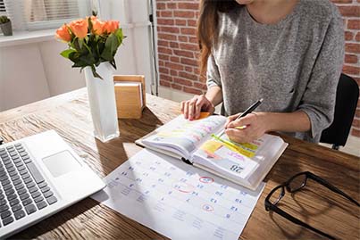 Businesswoman marking annual return filing deadline on a calendar and planner Businesswoman marking annual return filing deadline on a calendar and planner