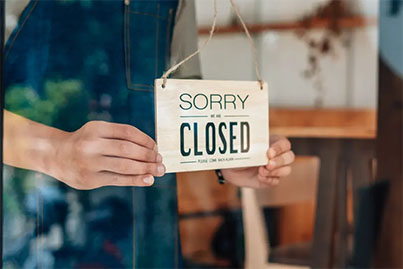 closing your business Shop owner hanging a 'Sorry We're Closed' sign, representing closing or dissolving a business
